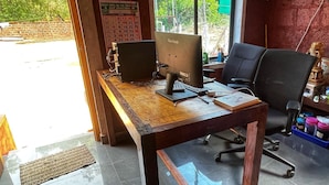 Uma mesa de madeira com dois computadores, uma cadeira e um calendário na parede.