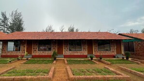 Um edifício de dois andares com telhado de telhas, paredes de tijolo e um pátio central com grama e caminhos.