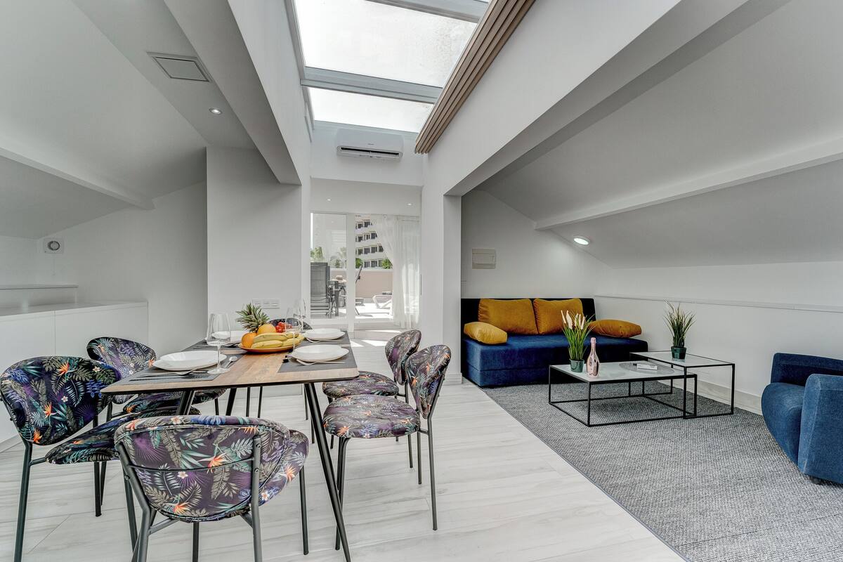 Un espacio habitable moderno con comedor, un conjunto de sofás y una mesa de centro.