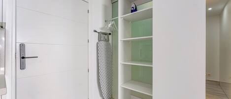 Un armario moderno con estantes blancos y una barra para colgar.
