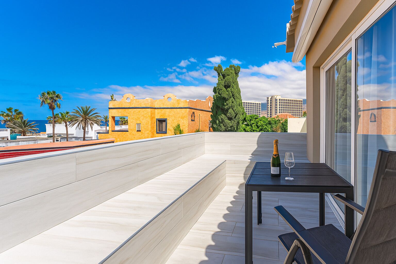 A balcony with a table, a bottle of champagne, and a glass.