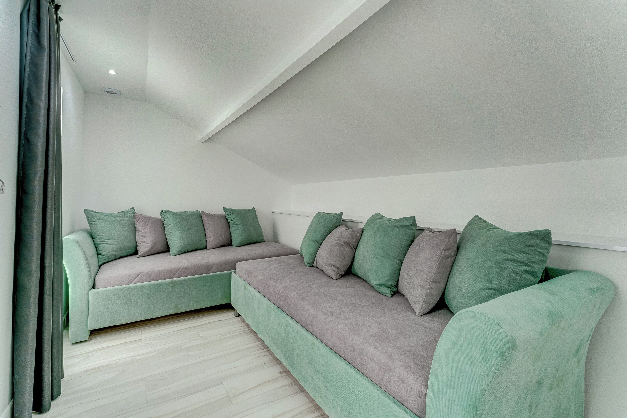 Un salon moderne avec un canapé d’angle, un téléviseur à écran plat et un luminaire fixé au plafond.