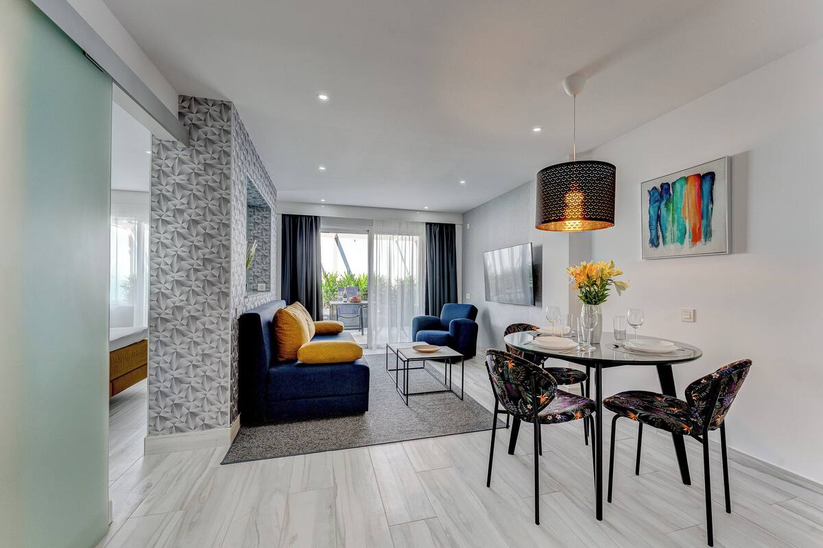 Una sala de estar moderna con sofá, mesa de centro y comedor con sillas y mesa.