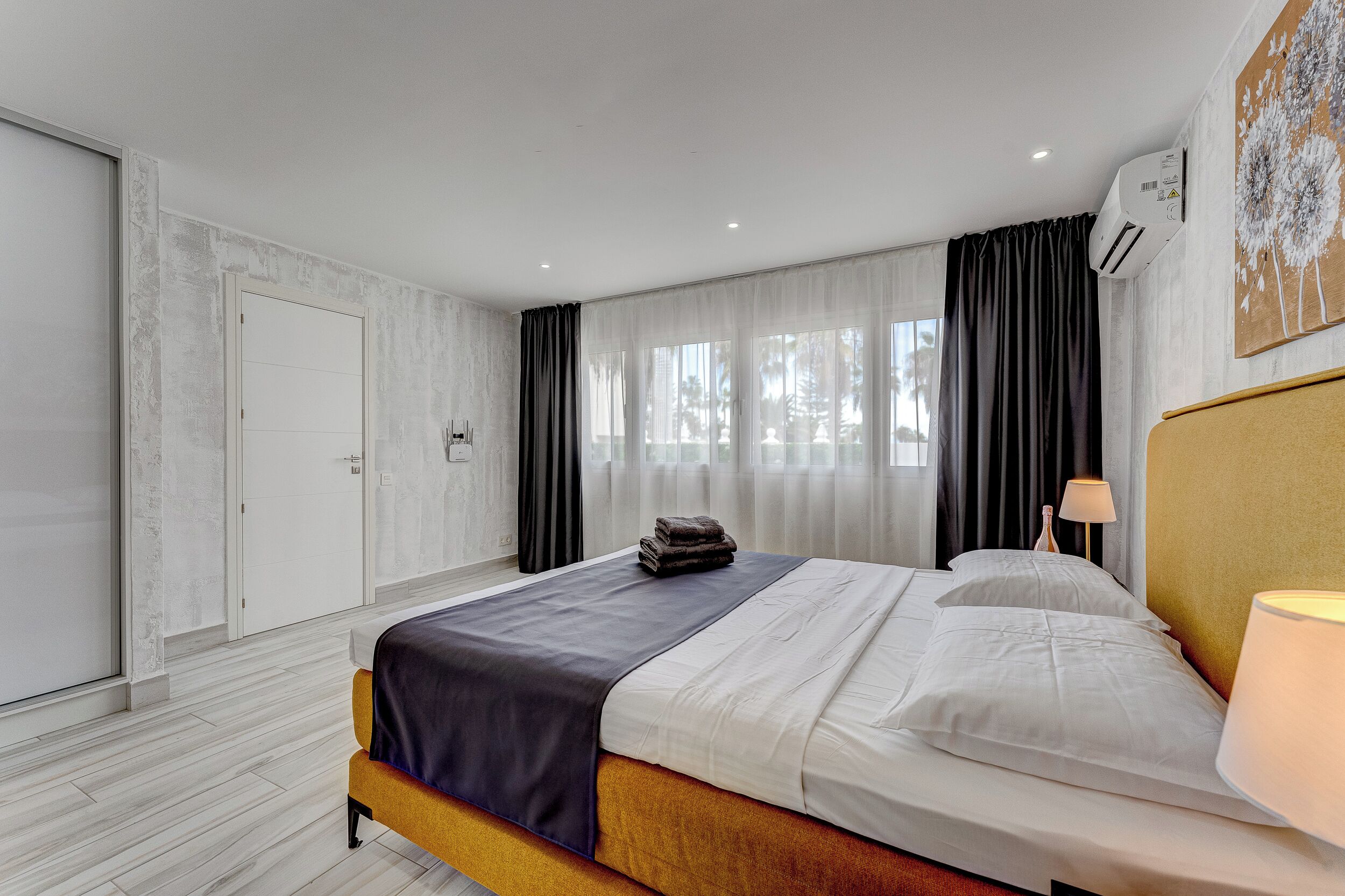 A modern hotel room with a large bed, a bedside lamp, and a window with curtains.