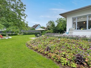 Un giardino curato con prato, una zona patio con mobili da esterno e un edificio con ampie finestre.