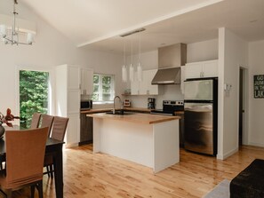 Une cuisine moderne avec des meubles blancs, un réfrigérateur en acier inoxydable et un îlot central en bois.
