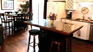 A kitchen with wooden cabinets, a refrigerator, a coffee maker, and a clock on the wall. - Ocean view 5-bedroom house in Narragansett with AC, WiFi, beach pass (Narragansett)