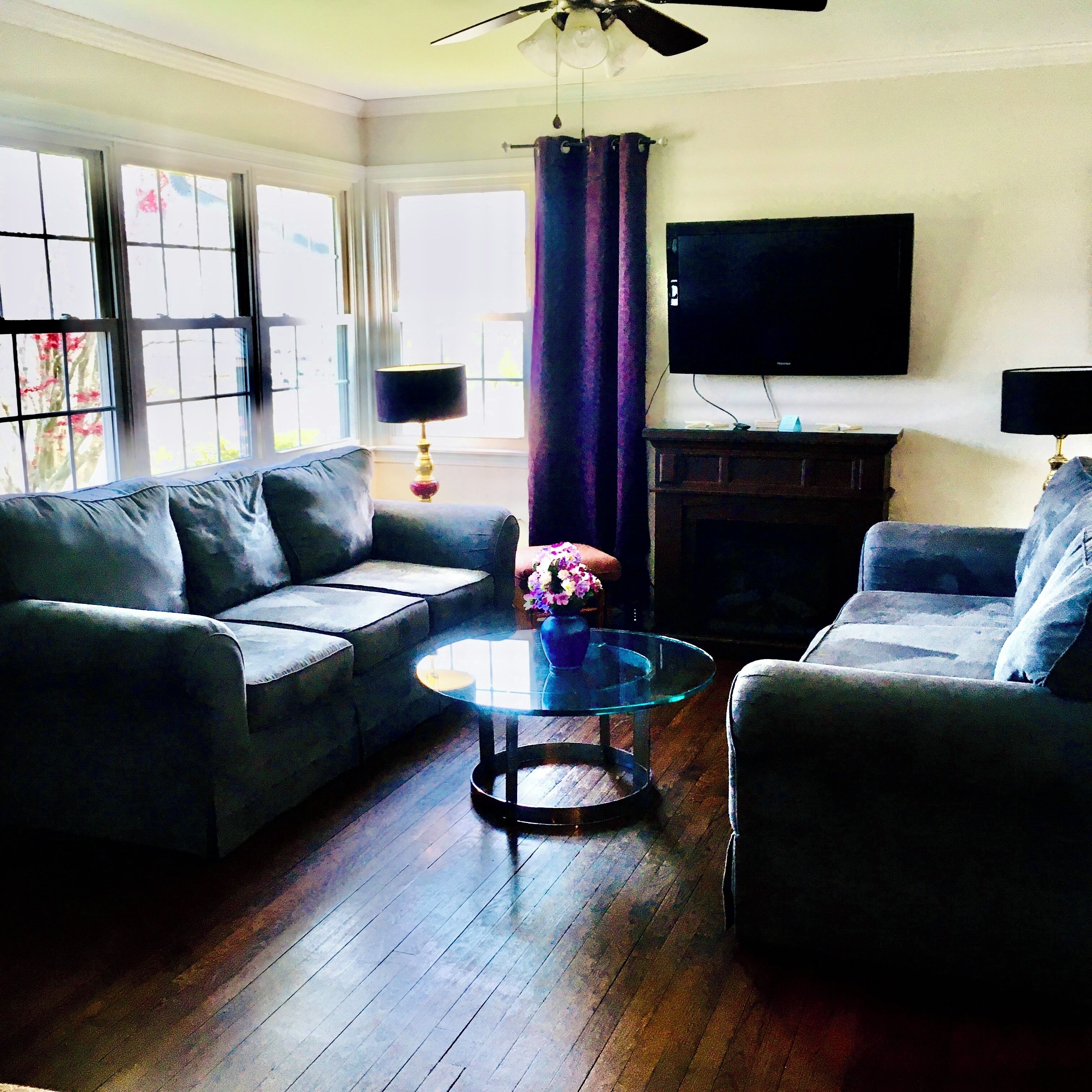 A living room with a sofa, armchair, and a glass coffee table.