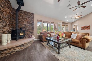 A cozy living room with a stone fireplace, a brown leather sofa, and a glass coffee table.