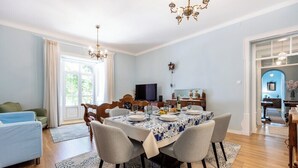 A dining area with a table set for four, a television, and a dining table with a blue and white patterned tablecloth. - Casa Matias - Stylish 4BR Apartment • Lagos Old Town (Lagos)