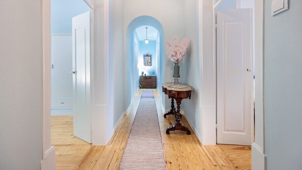 A hallway with wooden flooring, white walls, and a blue archway leading to another room. - Casa Matias - Stylish 4BR Apartment • Lagos Old Town (Lagos)