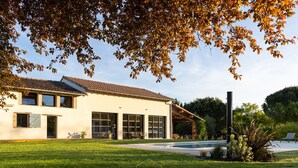 Une maison moderne à deux étages, dotée d’une grande pelouse à l’avant, d’une piscine et d’une pergola.