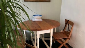 Une table ronde en bois avec un pied blanc, un bol bleu et blanc, et une paire de lampes noires fixées au mur juste au-dessus.