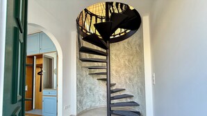 Eine Wendeltreppe mit strukturierter Wand dahinter, die zu einem Raum mit einem blauen Schrank und einer Tür führt.