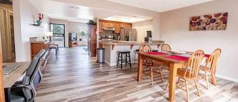 A spacious kitchen with wooden cabinets, a dining area with a wooden table and chairs, and a large window providing natural light.