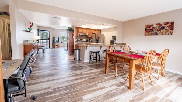 A spacious kitchen with wooden cabinets, a dining area with a wooden table and chairs, and a large window providing natural light.