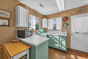 Kitchen with central island, microwave, stove, and sink, featuring a decorative fish above the door.