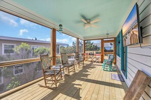 A wooden deck with rocking chairs and a TV.