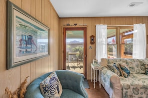 Relax in this inviting living room with a sofa, armchair, and sliding door leading to a patio with a mountain view.