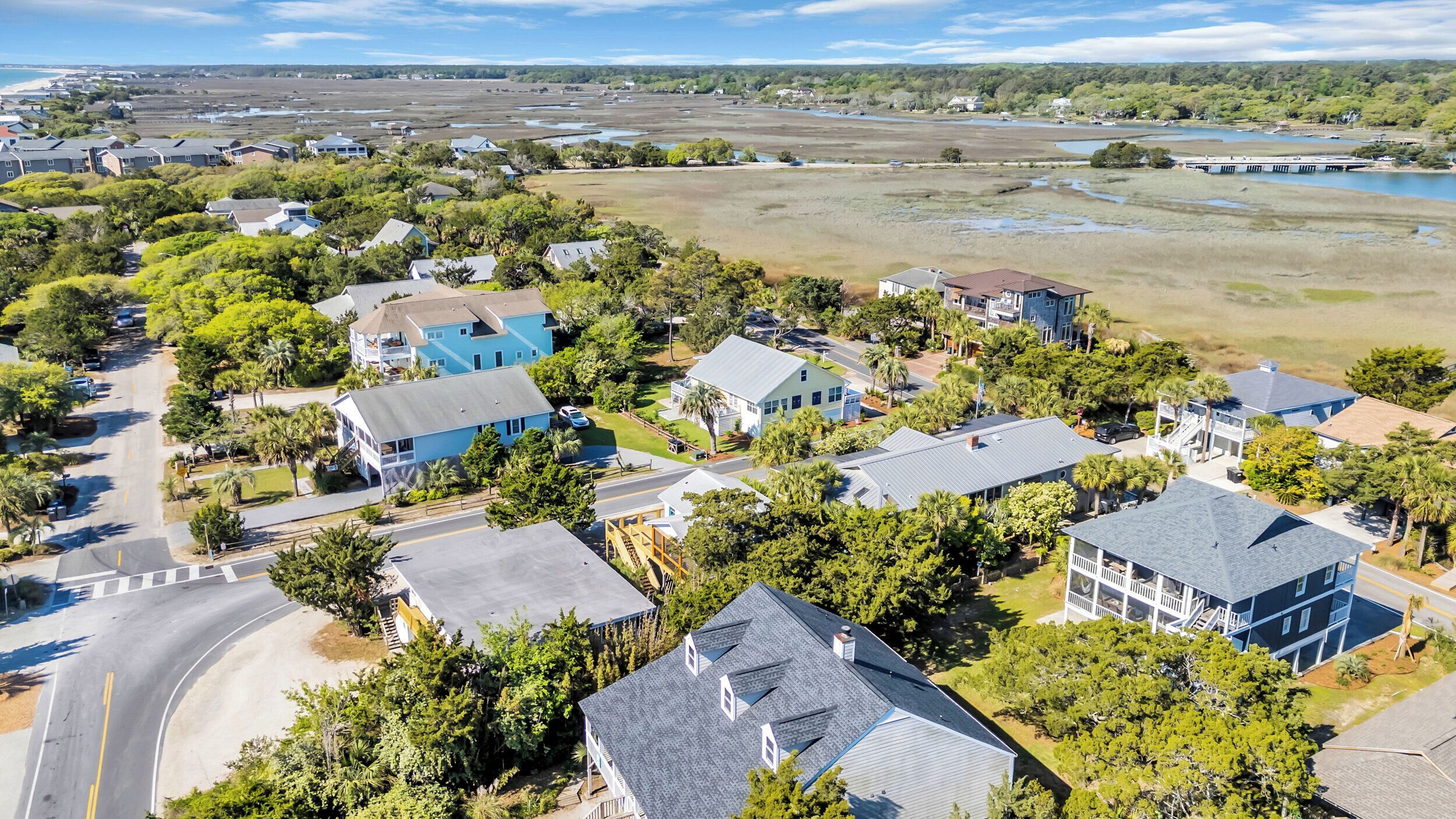 An aerial view of a residential area with houses, roads, and a beach in the background.
