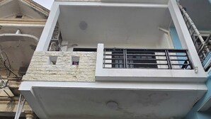 Un edificio residenziale a più piani con facciata bianca, un cancello nero e un balcone al piano superiore.