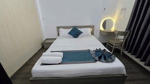 A neatly made bed with pillows and a blanket, a bedside table with a lamp, and a chair with curtains. - MUBEE Homestay (Hue)