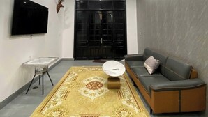 Un soggiorno moderno con un divano, un tavolino, una TV e un tappeto decorato.