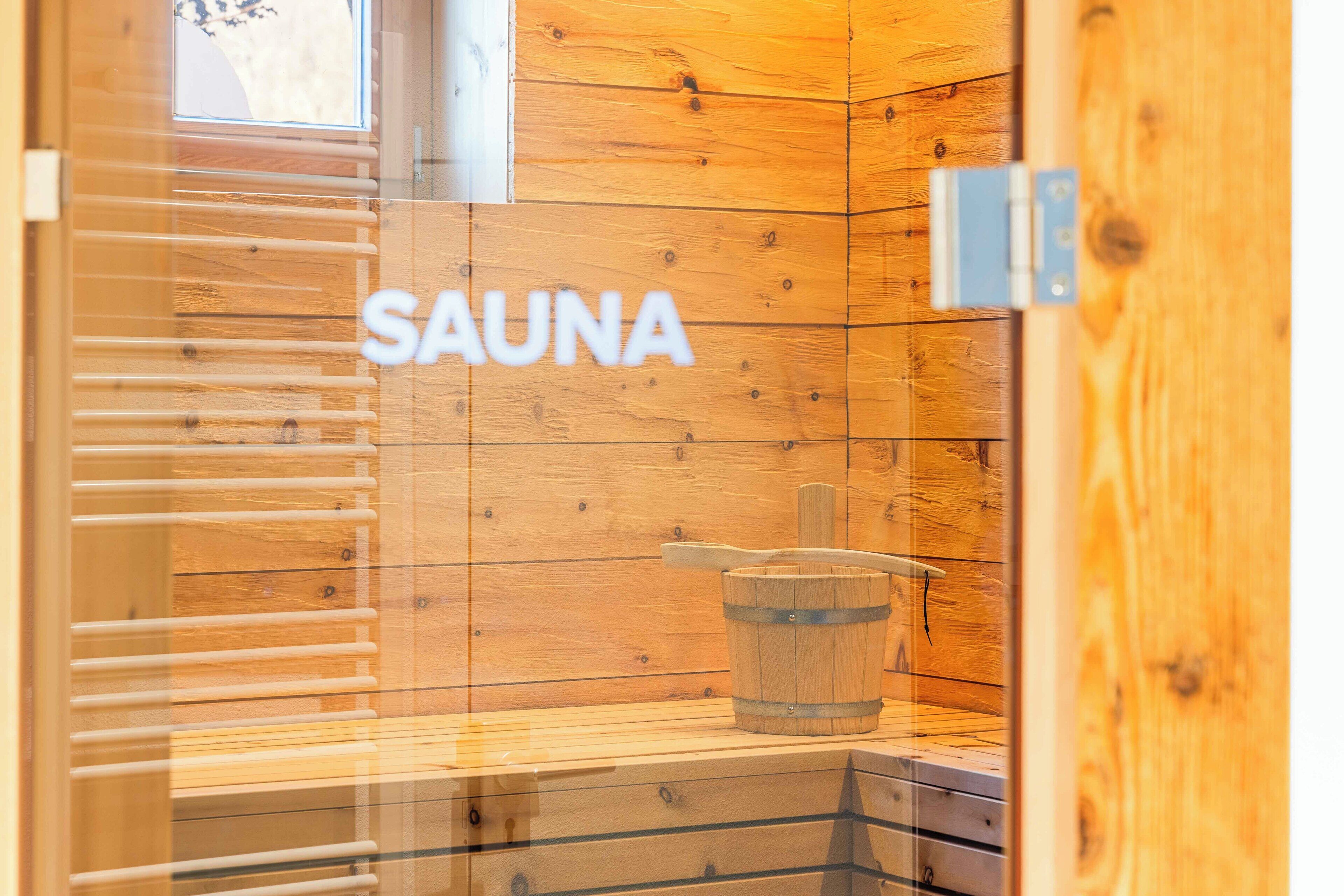 Een sauna met houten wanden en een bordje met de tekst 'SAUNA'.