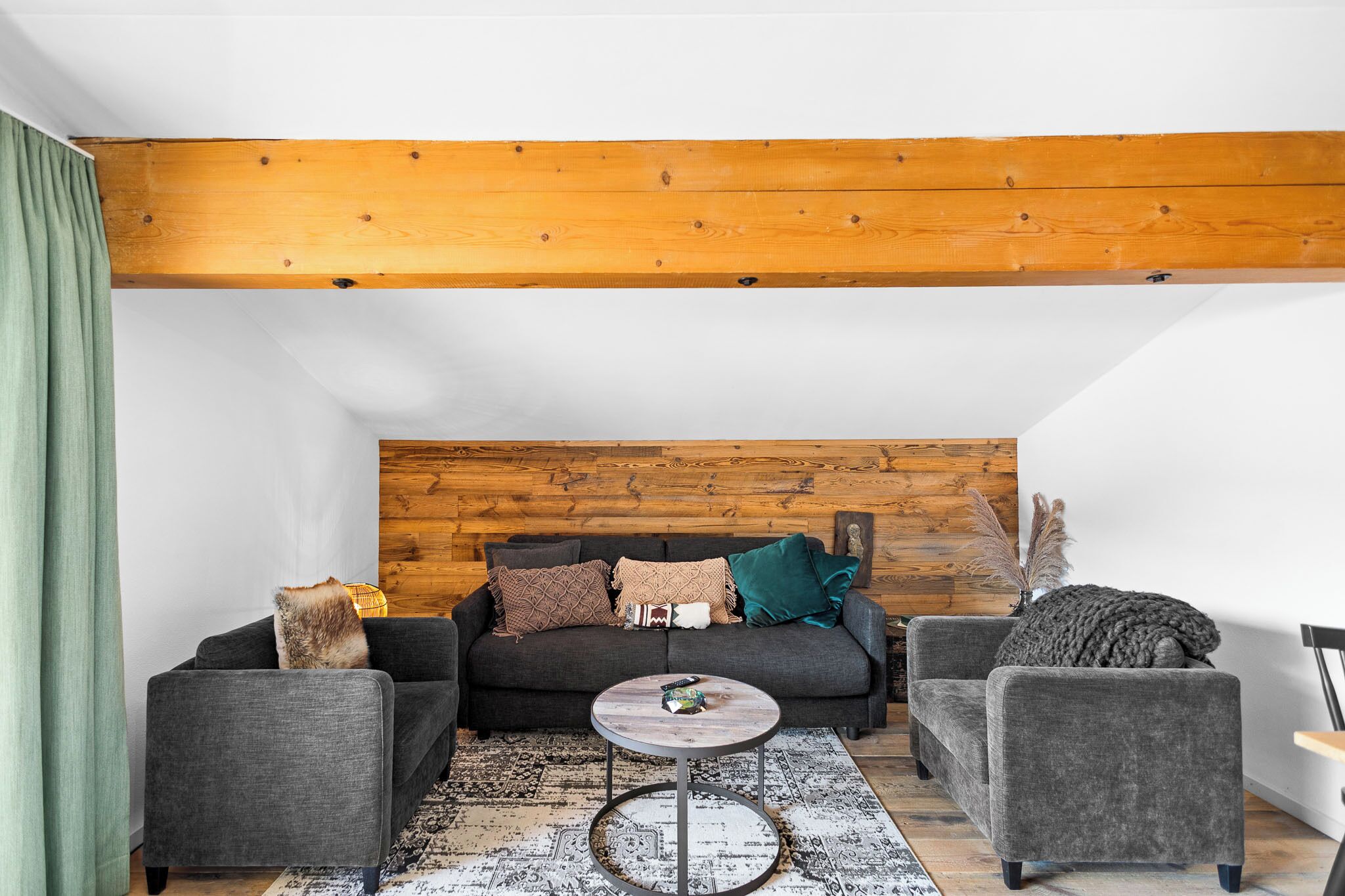 Un salon moderne avec un canapé gris, une table basse ronde et un plafond en bois.
