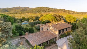 A stone building with a tiled roof, surrounded by lush greenery and a pool. - Villa San Girolamo (Toscana)