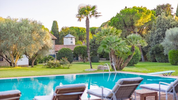 A swimming pool with lounge chairs, surrounded by a well-maintained garden and a house in the background. - Villa San Girolamo (Toscana)