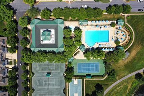 Vista aérea de uma propriedade com piscina, quadras de tênis e área coberta com assentos.