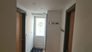En hall med dörrar av trä, en vit vägg och en dörr med en klocka.