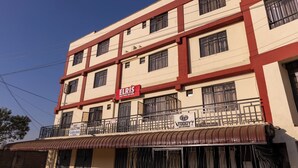 A multi-story building with a red and white facade, featuring a sign for 'ELRIS Guest House & Hotel' and a 'TODDY' bar and restaurant.