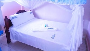A single bed with a canopy, white bedding, and pillows with "ELRIS GUEST HOUSE" text.