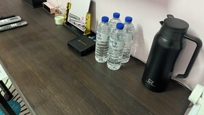 A desk with a water bottle, a thermos, a tissue box, a calculator, and a small candle. - Lukang Hung-shiu Homestay (Lukang)