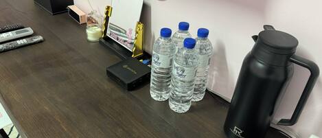 A desk with a water bottle, a thermos, a tissue box, a calculator, and a small candle.