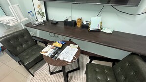 A hotel room with a round table, two leather chairs, a TV, and various amenities like a water bottle, tissues, and a card. - Lukang Hung-shiu Homestay (Lukang)