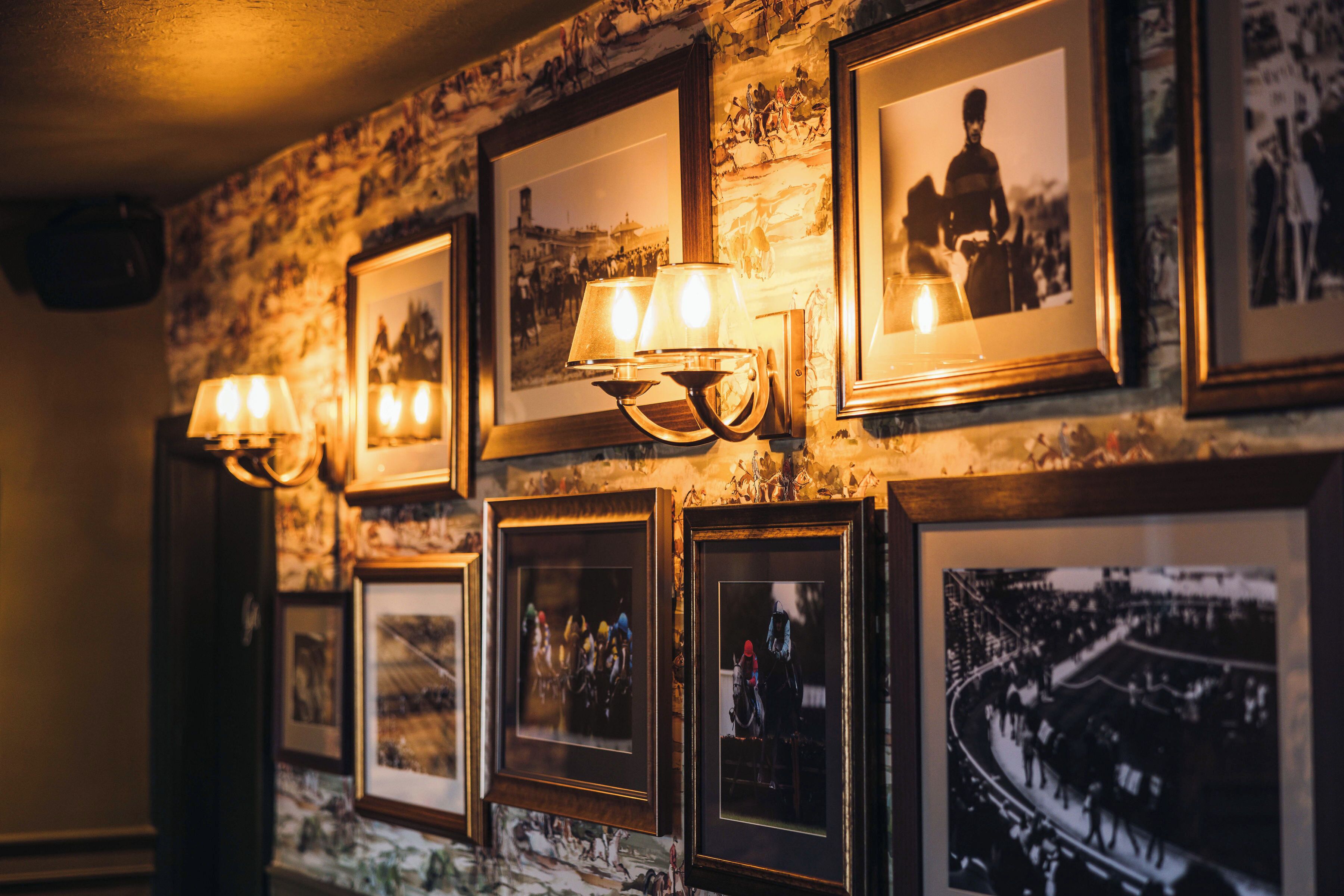A wall with framed photographs and wall-mounted lamps.