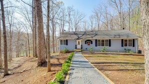 A house with a gravel driveway, surrounded by trees, and a clear sky.