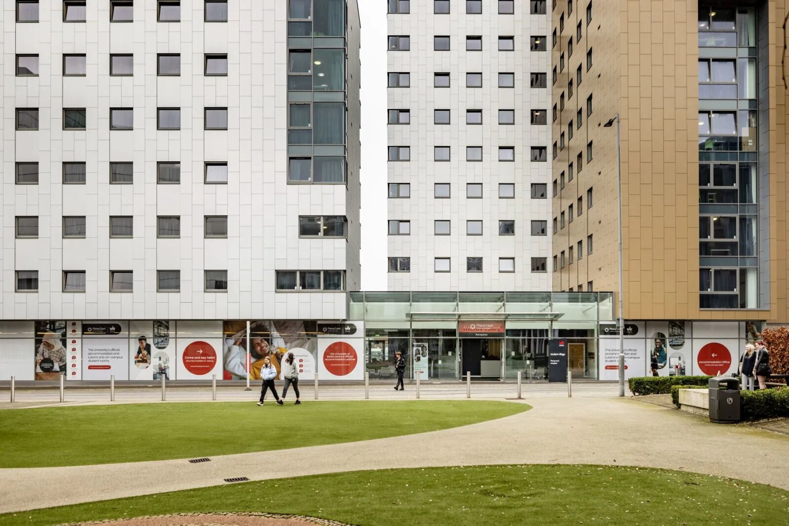 A modern building with a central entrance, surrounded by a well-maintained lawn and a pathway.