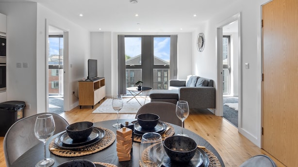 Una sala de estar moderna con comedor, ventanas amplias y vista a la ciudad.