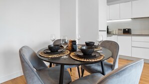 Un comedor moderno con una mesa redonda preparada para cuatro personas, rodeada de sillas tapizadas en gris.
