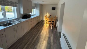 A compact kitchen with a sink, cabinets, and a dining area with chairs and a table.