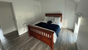 A bedroom with a wooden bed, white walls, and a radiator.