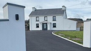 A two-story house with a front entrance, a driveway, and a grassy area.