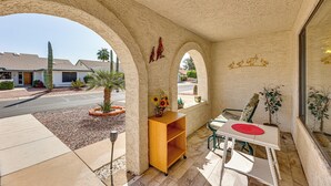 Un patio abrité avec une table et des chaises, une étagère en bois et des plantes en pot.