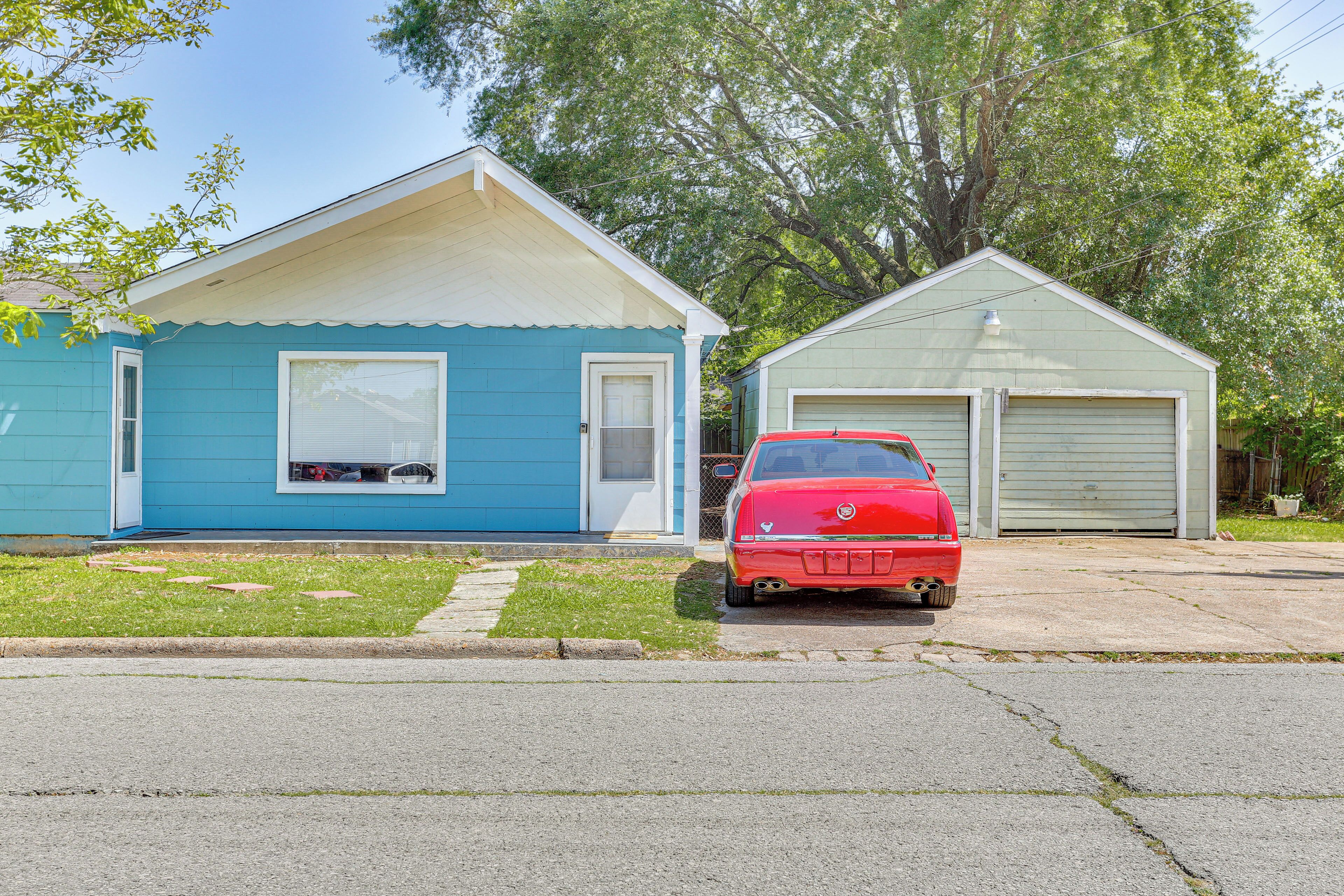 A residential street with two houses, one blue and one green, and a red car parked in front of the green house.