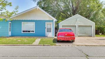 A residential street with two houses, one blue and one green, and a red car parked in front of the green house.