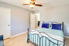 Een slaapkamer met een bed, een plafondventilator en een deur.
